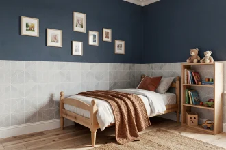 Chambre garçon avec mur moitié peinture bleu marine et moitié papier peint géométrique gris et blanc, lit en bois avec plaid en laine, parquet naturel et tapis tressé