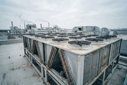 Vue en grand angle d'un dry cooler industriel installé sur le toit d'une usine moderne, mettant en valeur les ailettes en aluminium et les ventilateurs axiaux