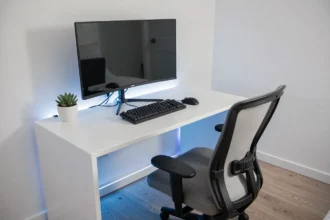 Setup gaming minimaliste avec bureau blanc, moniteur ultrawide et éclairage RGB bleu discret dans une chambre épurée